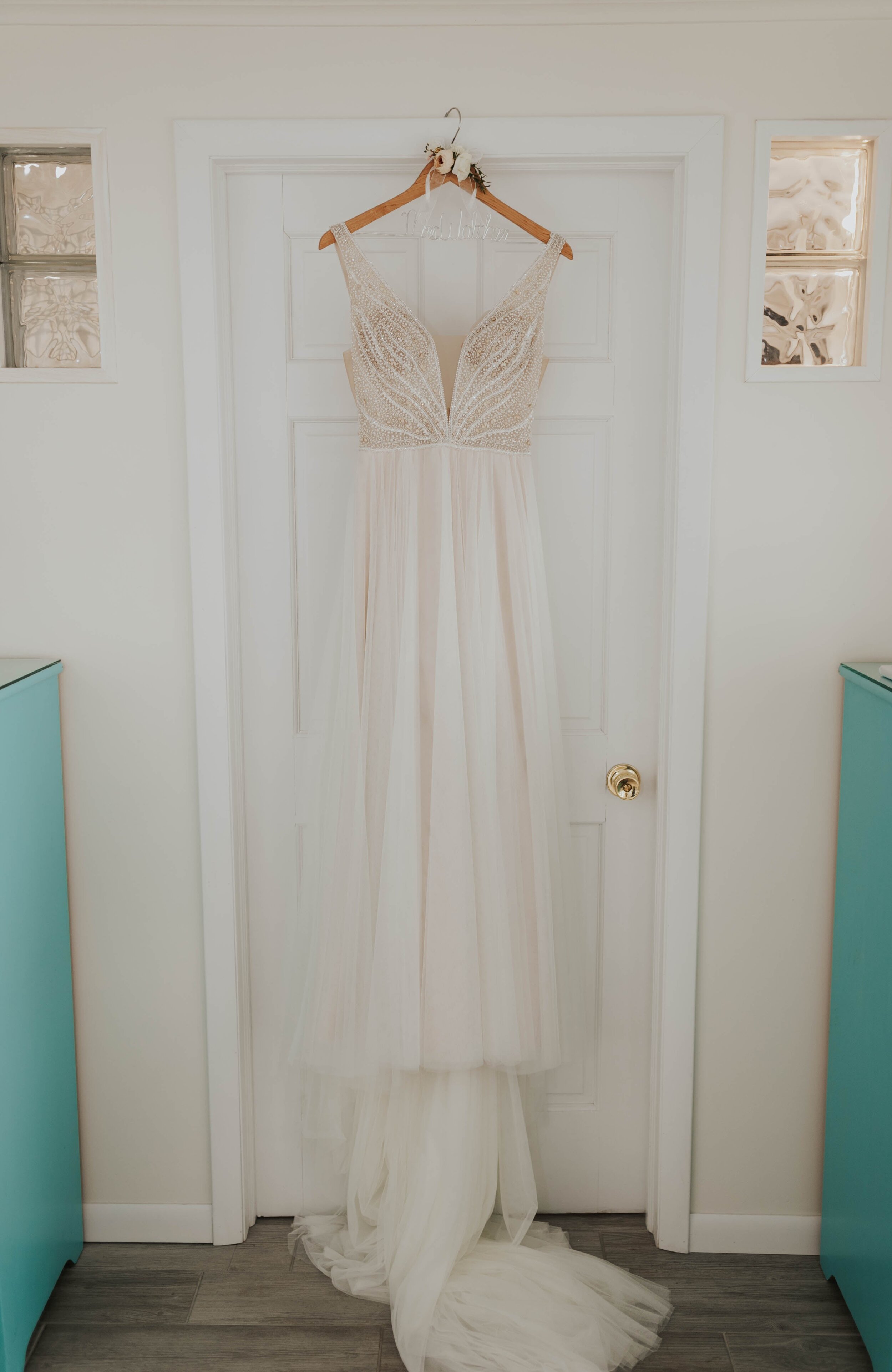 bridal gown hanging from door on wooden hanger