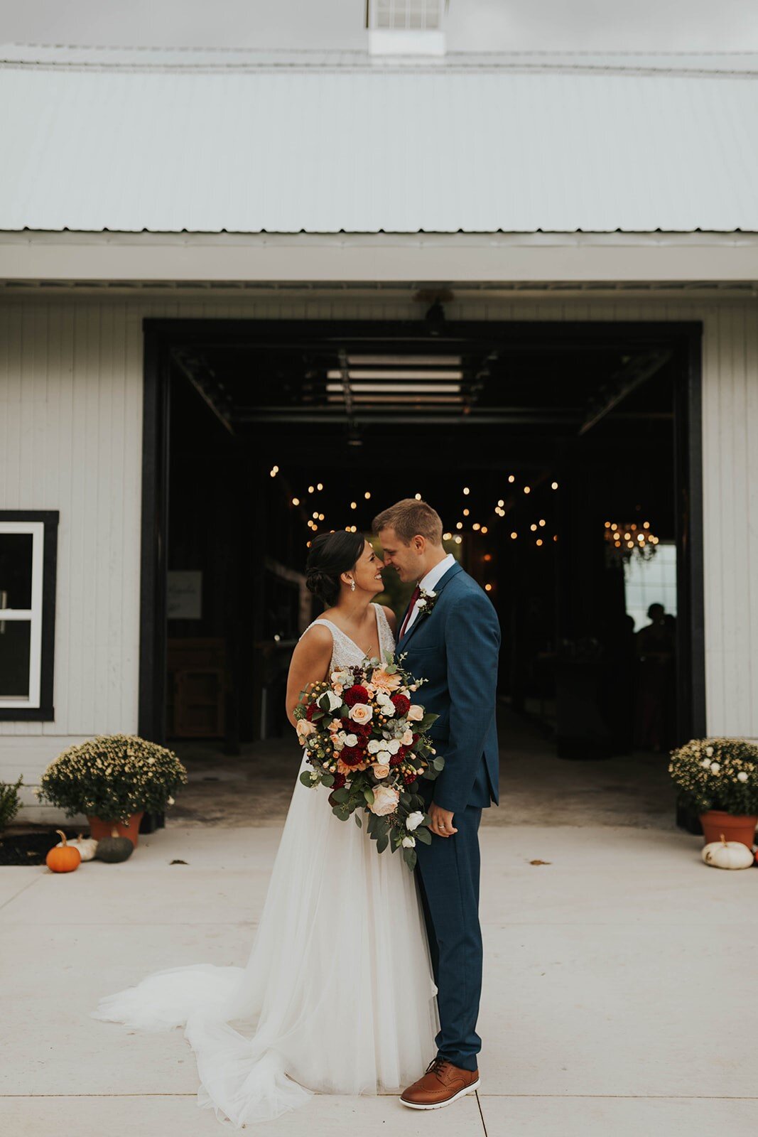 bride and groom standing outside of barn wedding