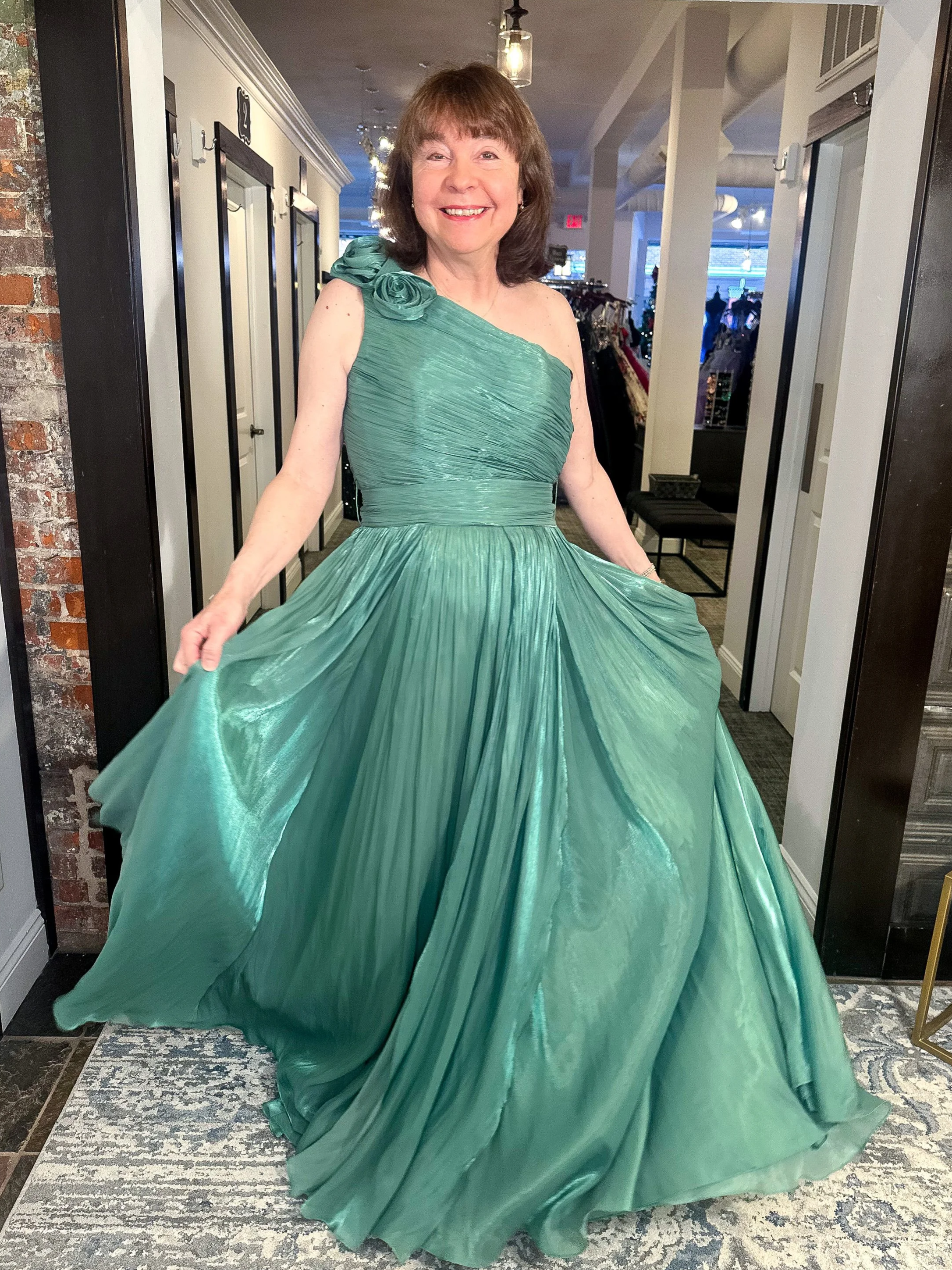 wedding party standing behind bride and groom, cheering for them as bride and groom fake arm wrestle.