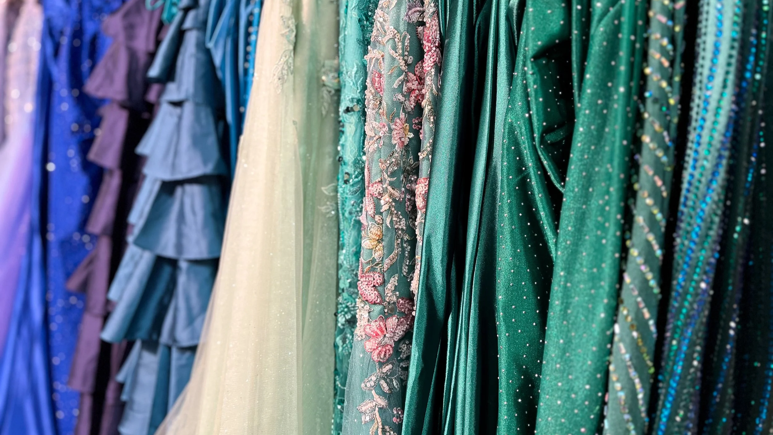 In store photo of prom dress selection, multiple circular racks of dresses.