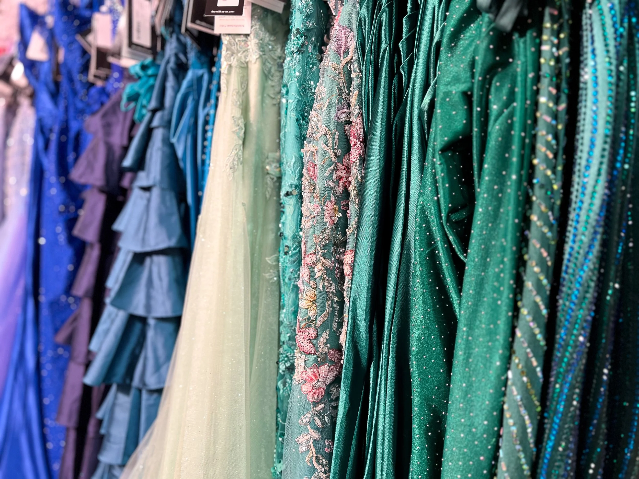 close up of pageant dresses in all different colors, most of them beaded.