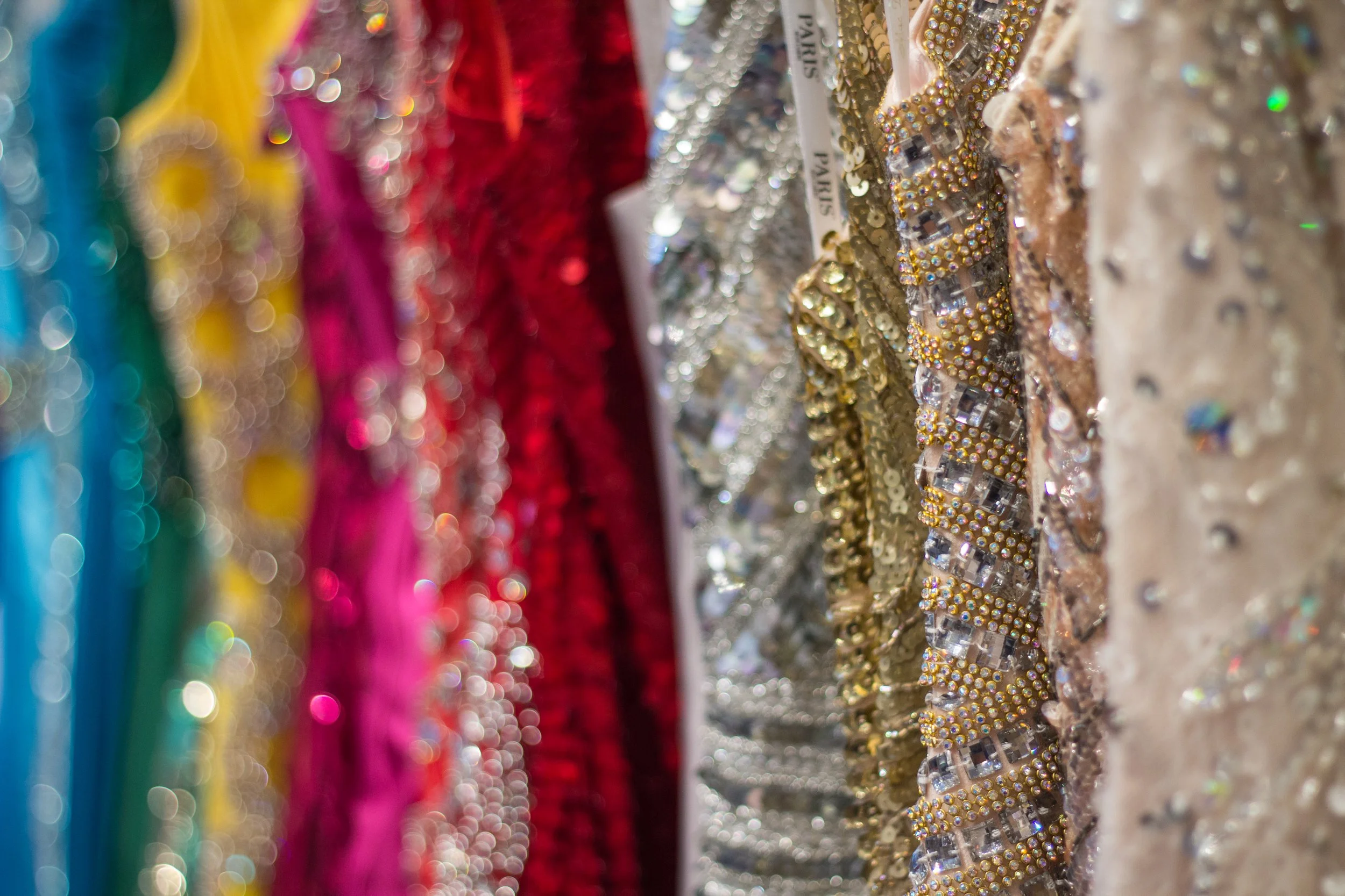 close up of pageant dresses in all different colors, most of them beaded.
