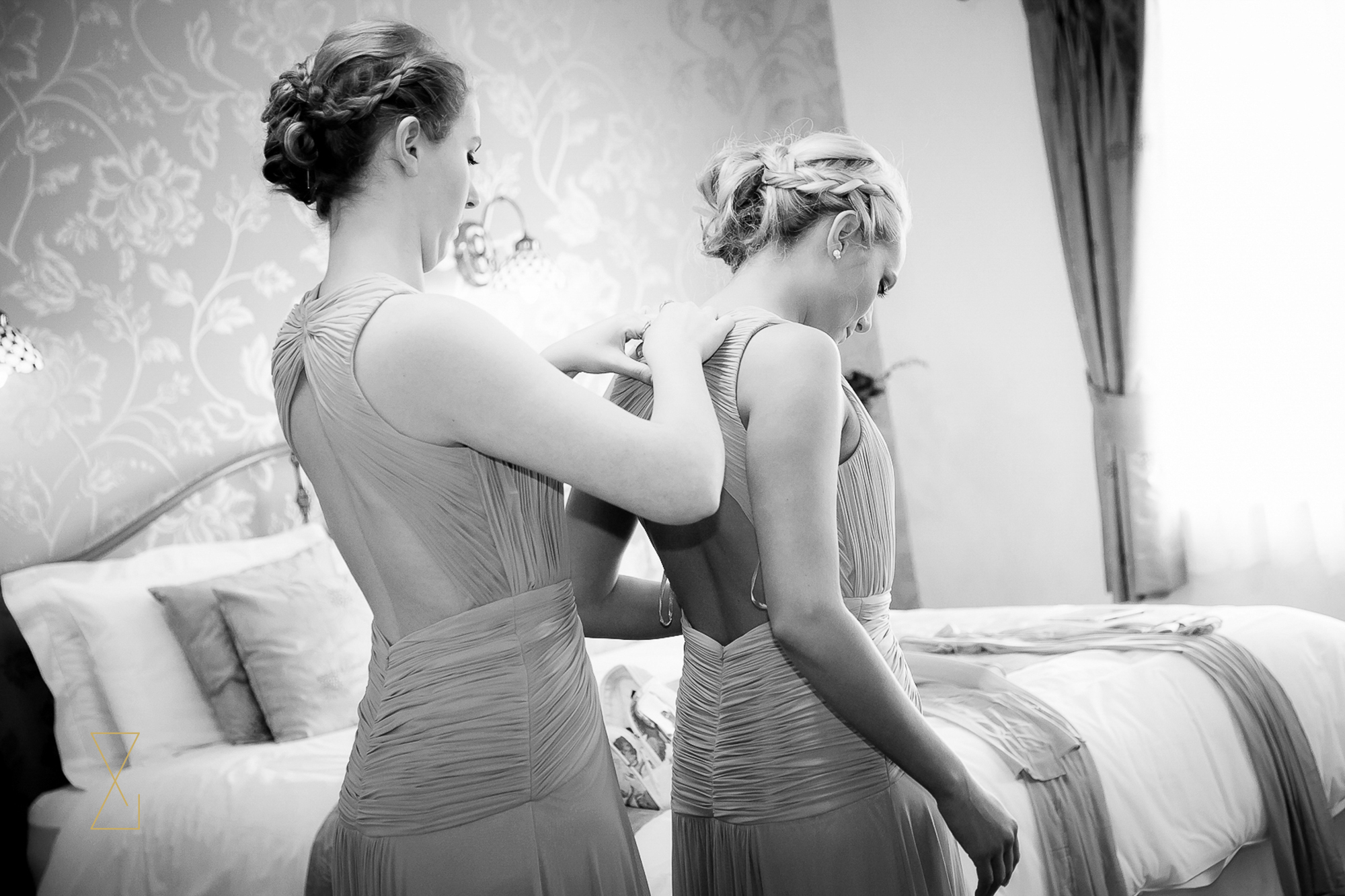 Bridesmaids helping each other into their dresses at Heaton House Farm, Evans & Evans wedding photography