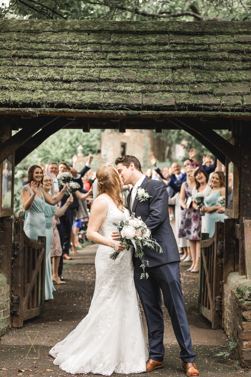 Bride-and-groom-kiss-lych-gate-St-James-Gawsworth-wedding