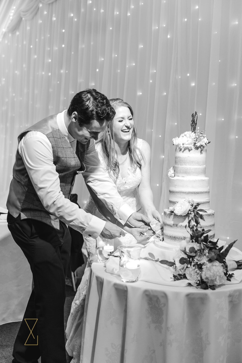Bride-and-groom-laughing-while-cutting-wedding-cake