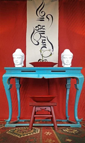 Our 2013 Thanksgiving storefront window, featuring a blue antique Chinese altar table, handwoven Dhurrie wool rug, and Tibetan manuscript painted by local artist and AHI design consultant Emily Henderson. The vertical design translates to “courage of the heart’s will.”