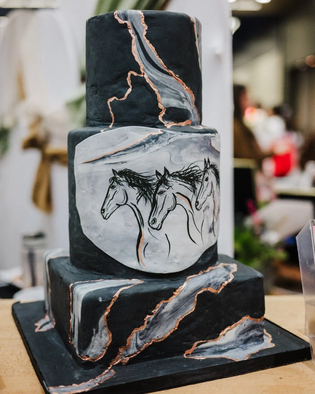 Year of the Fire Horse energy&hellip; but make it wedding. 🔥🐎

This cake stopped us mid-walk at the show. Moody black tiers. Marble movement. Copper detailing that feels like flame running through stone. And the hand-painted horses? Powerful, bold,