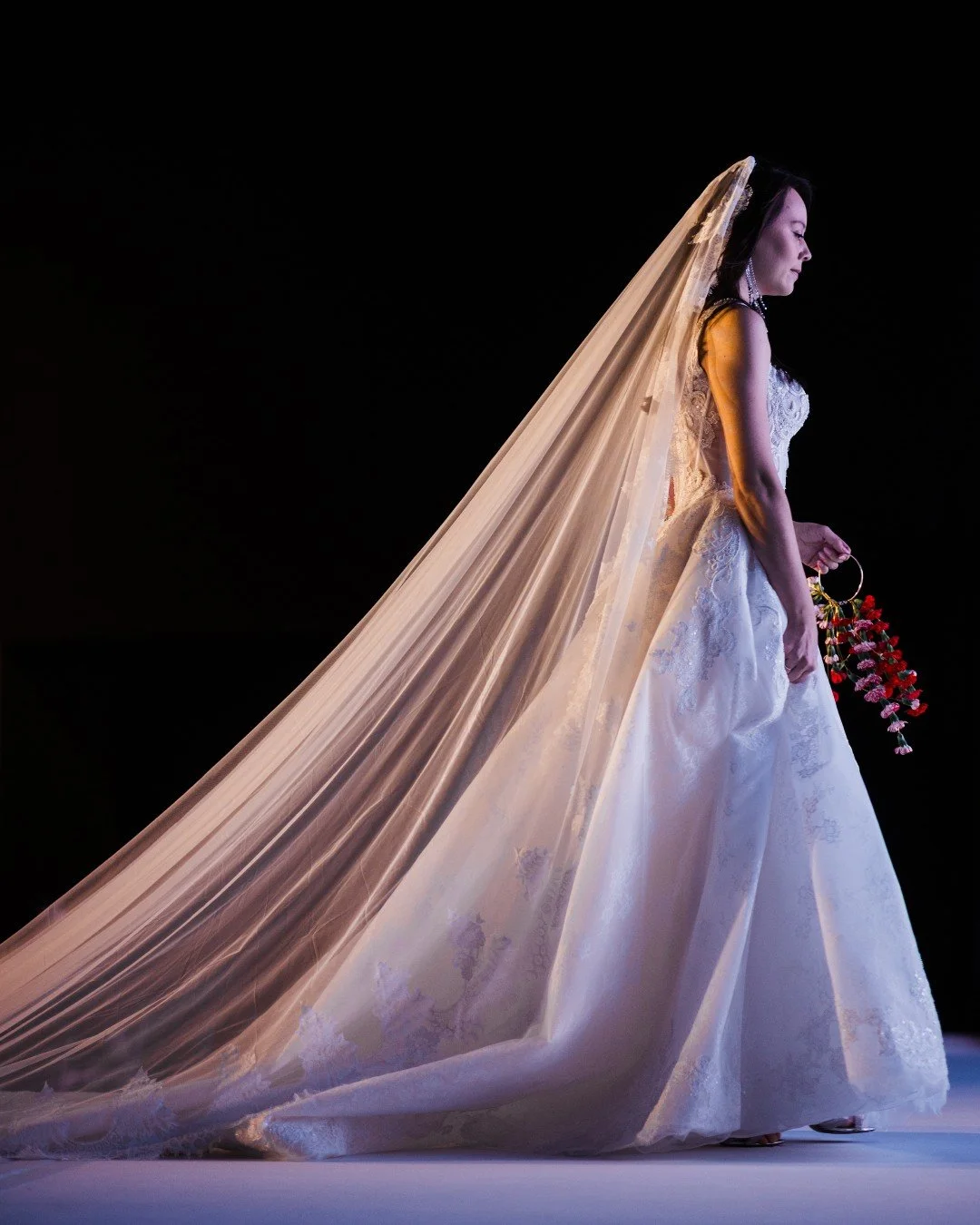 A breathtaking moment on the runway. ✨

This timeless gown paired with a dramatic flowing veil created a stunning silhouette. The delicate floral arrangement adds the perfect touch of color and romance. 

From the lace details to the cascading veil a
