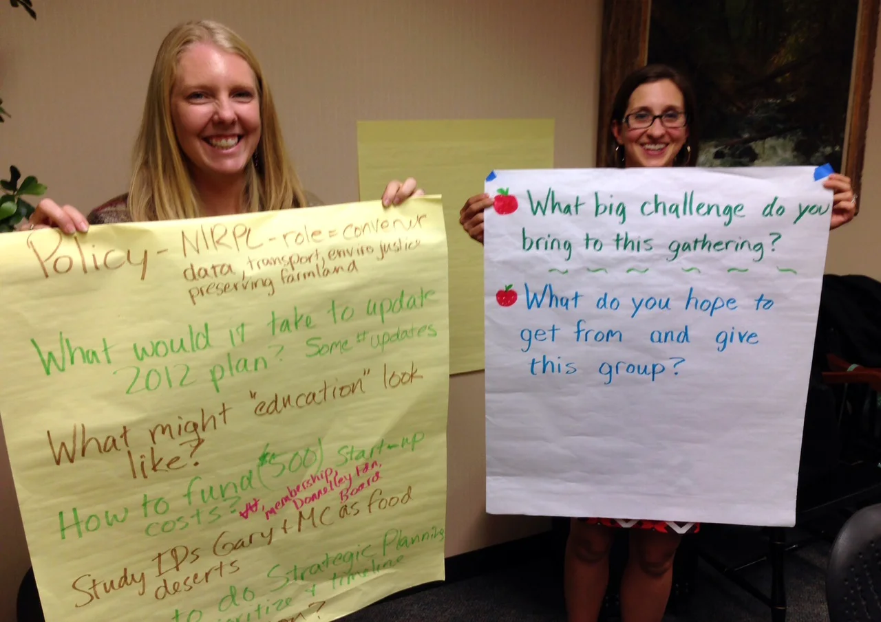 Lyndsay Ploehn and Nicole Negowetti hold up pages during a 2015 brainstorming session of the Task Force to Create an NWI Food Council.