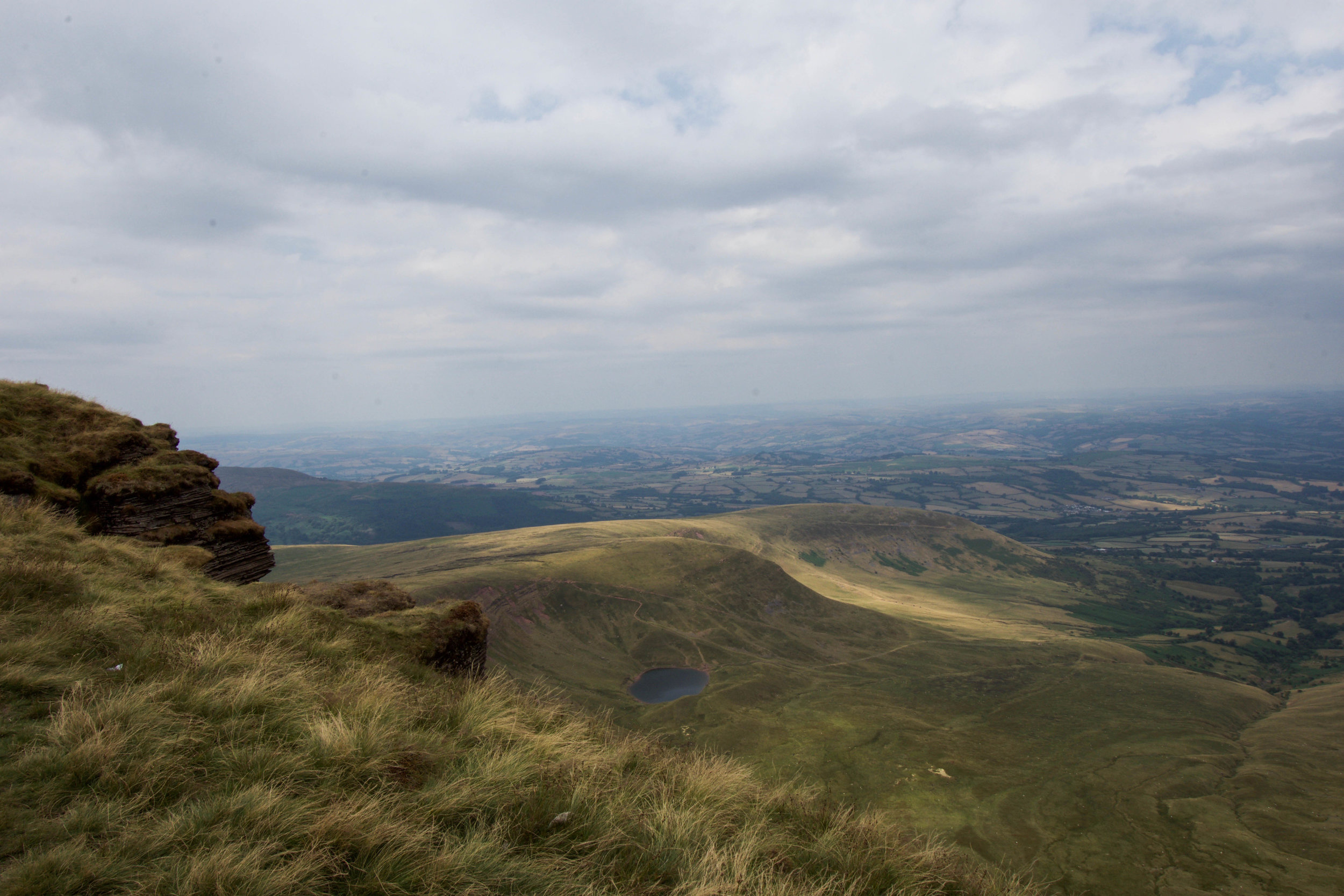 A view of the expansive green plains of Brecon Beacons National Park from atop Pen Y Fan, the tallest peak in the pastoral region of South Wales.