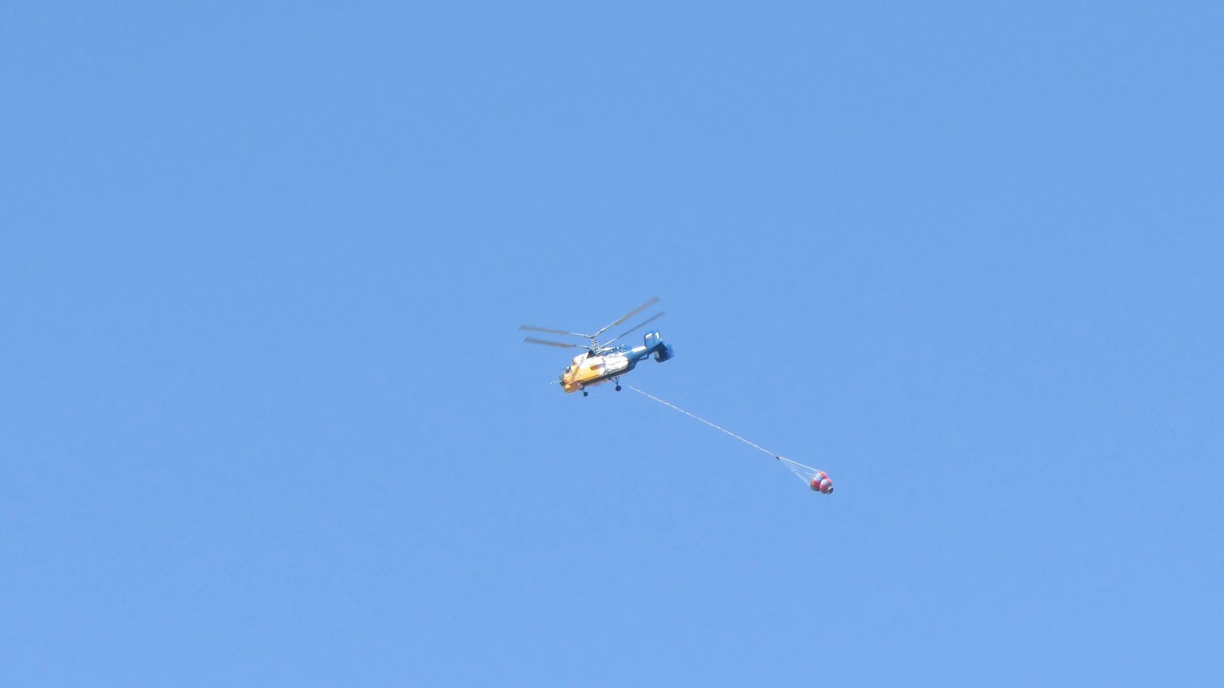 Firefighting helicopter on route to yet another fire in the mountains. The water container was filled with seawater and will be dumped on the fires raging in remote area's.