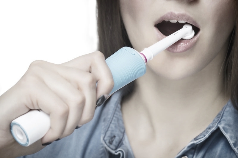 Lady brushing teeth with an electric toothbrush