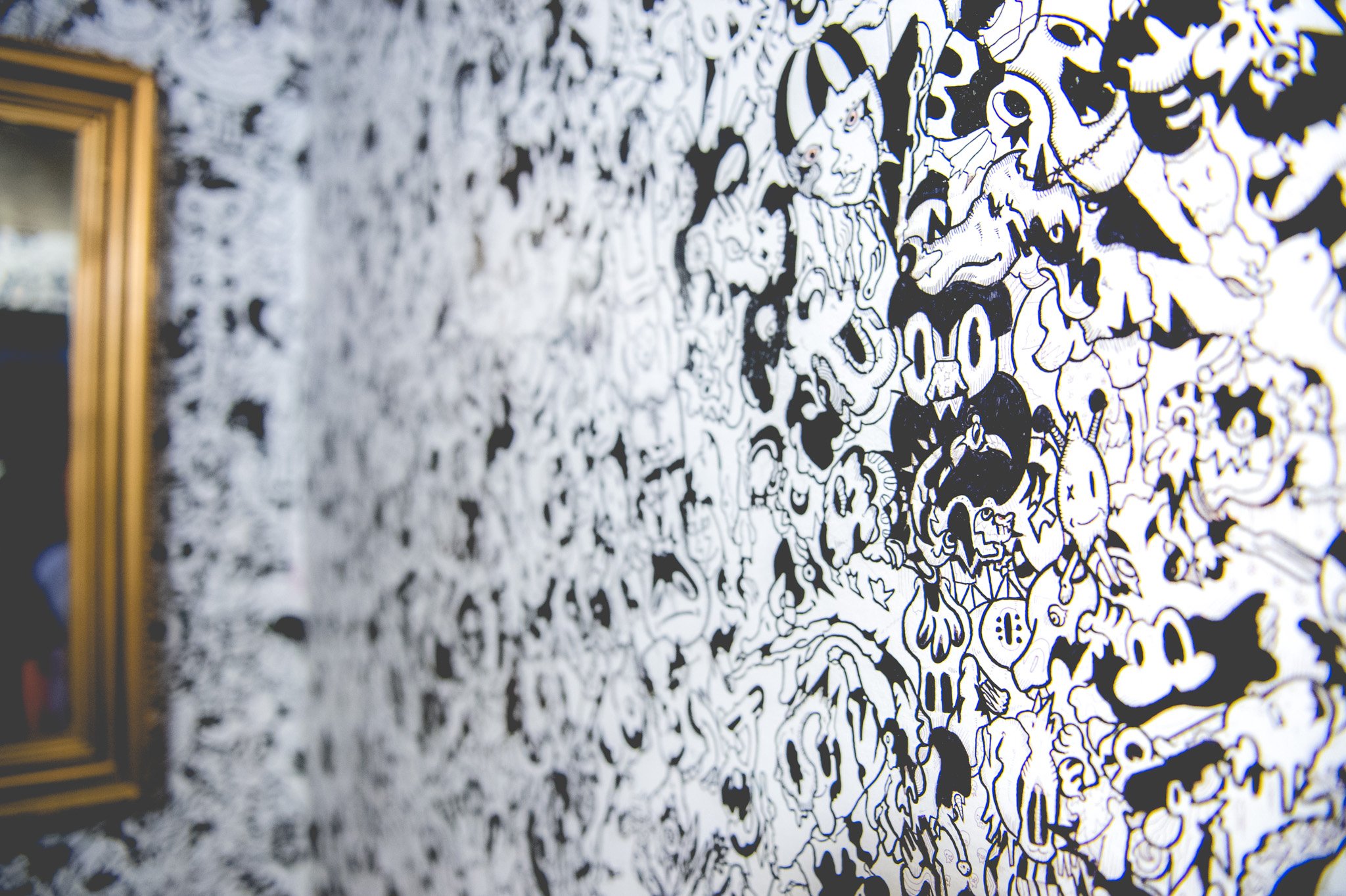 Close-up of a black-and-white mural with cartoonish characters and abstract designs, partially visible on a wall.
