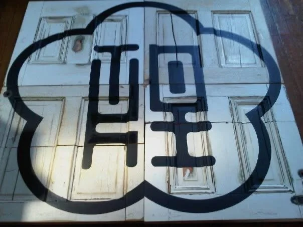 Painted street art of the word 'YES' inside a speech bubble on a white garage door.