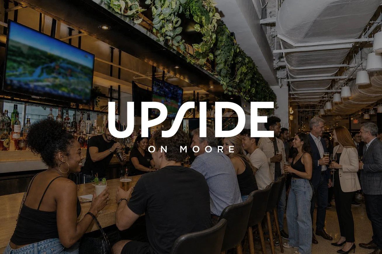 People socializing and drinking at a bar with a modern interior, greenery, and multiple television screens.