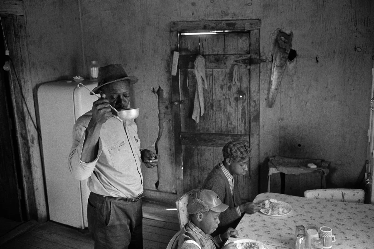 CONSTANTINE MANOS, Untitled, Sharecroppers, South Carolina (interior, man drink from a ladle 2 children), 1952