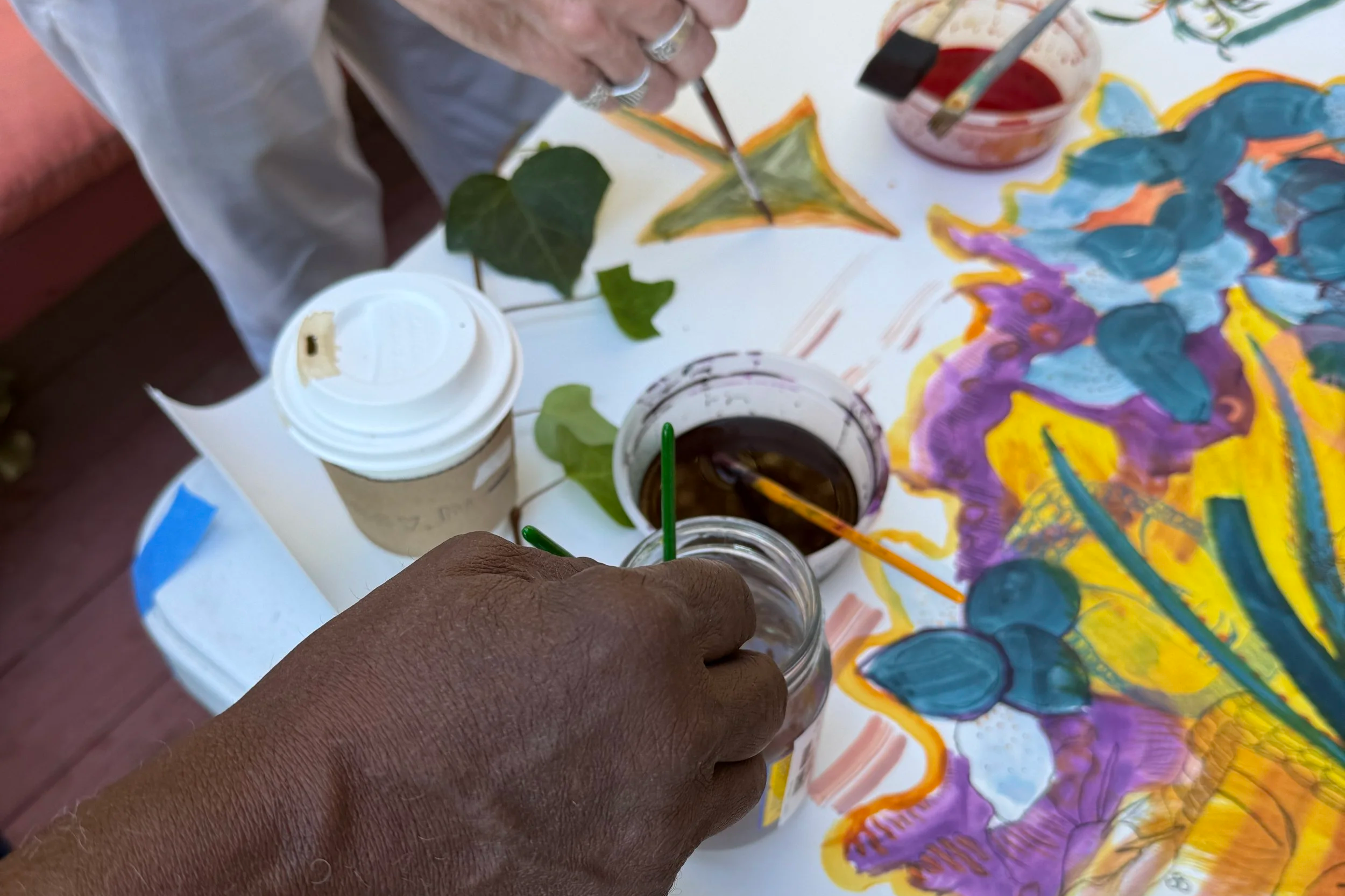 two men's hands are seen painting on a shared peiece of paper for Artist Amanda Mears' Leaving Earth Artist Book Project