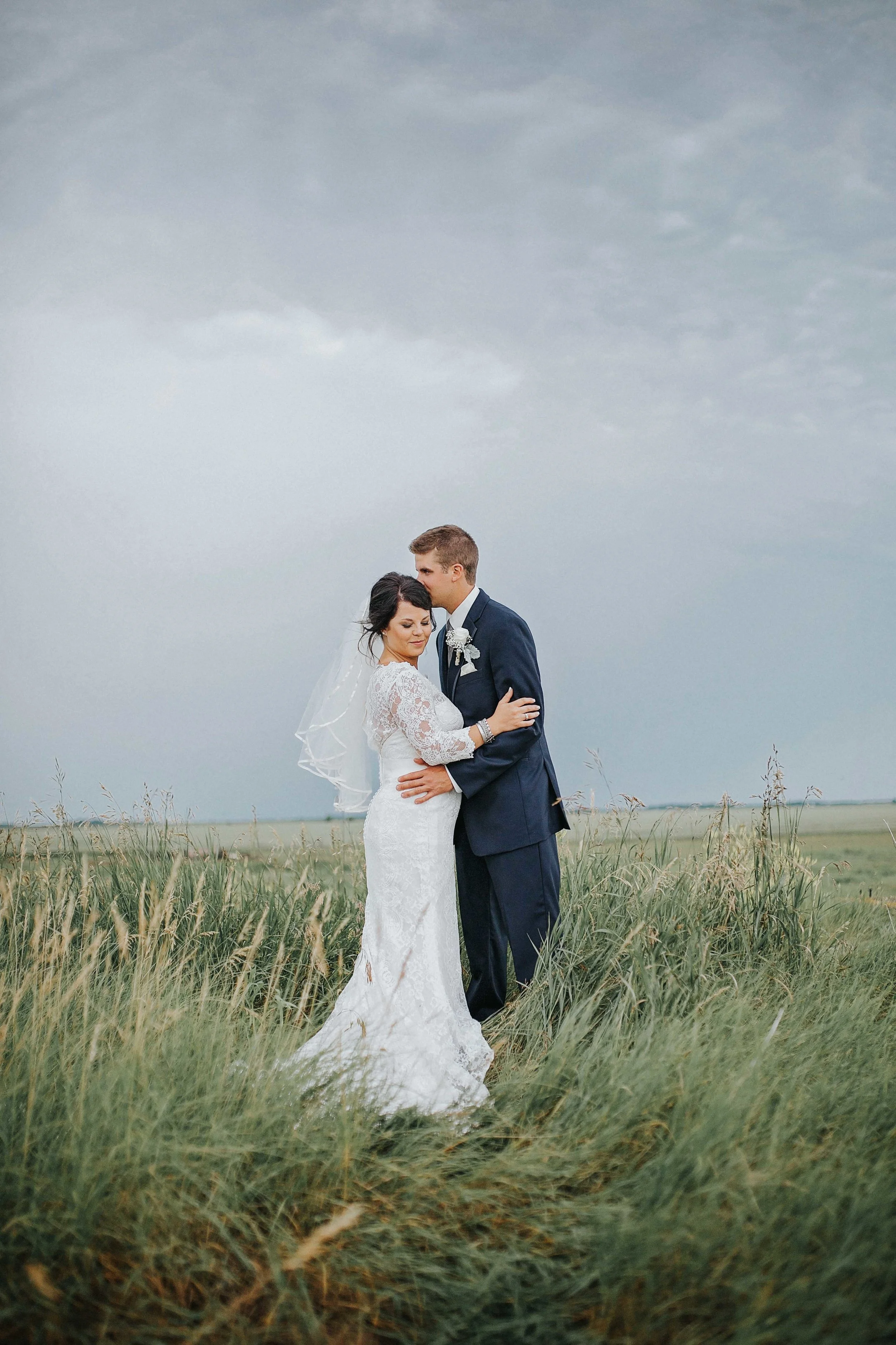 I remember this day not only because of how amazing Renee + Keaton's wedding looked but how much it rained. Did I mention their ceremony was outside. It rained so hard the entire day and night. They were so awesome that they just went for it anyways and it all turned out absolutely remarkable. I love a good ol rustic wedding, with endless amounts of lace and babies breath. Renee was an absolute beauty and Keaton of course cleaned up real nice. The two of them celebrated their marriage on the family farm with the most charming surroundings. The farm life means so much to these two that they incorporated canola fields, farm machinery and the coolest granary bar hut ever! 
