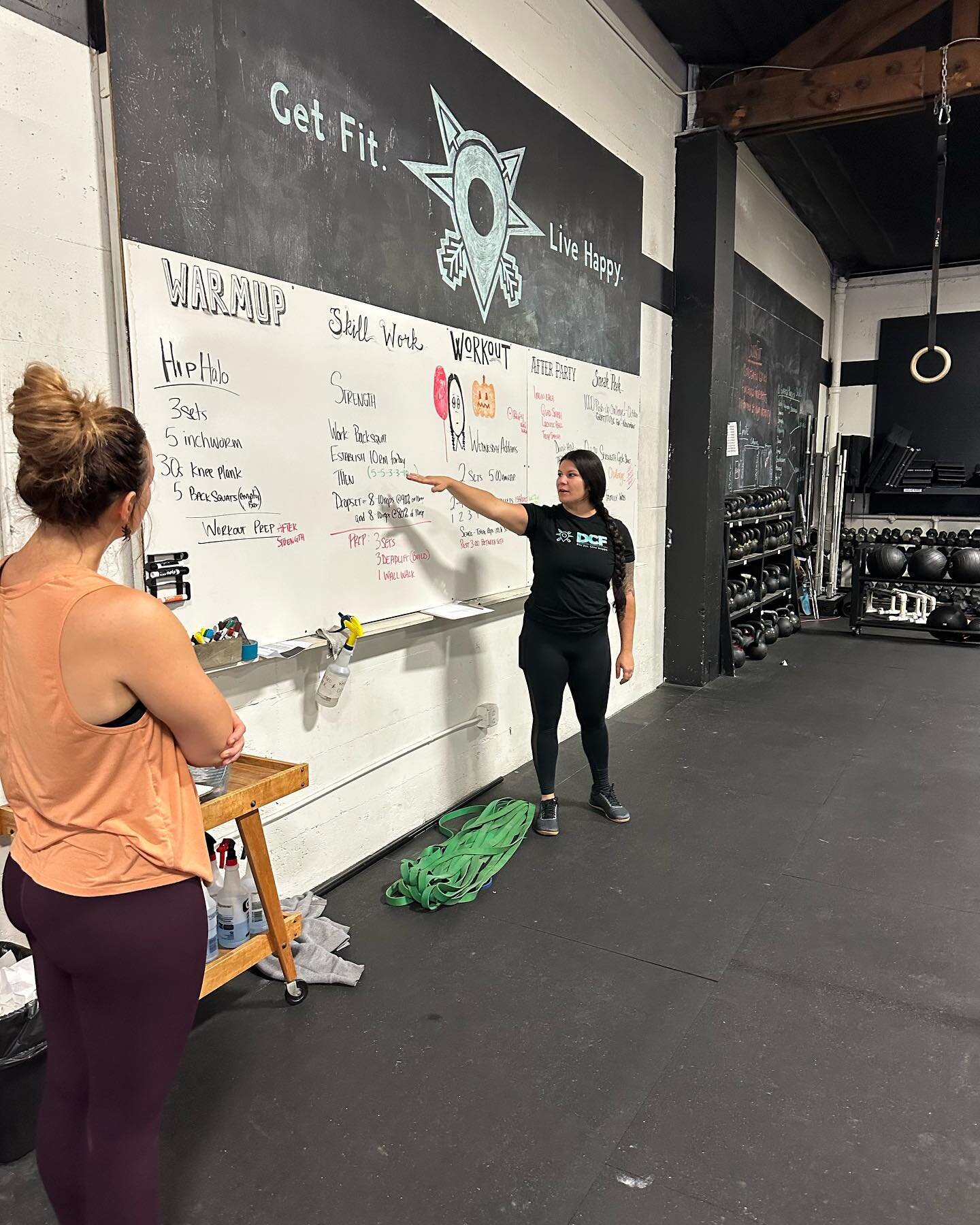 At the whiteboard:
At the start of every class we brief our members on the workout we are doing that day. We keep it short and sweet! Complete with the intended stimulus and goals for the workout and modifications to get there. We love to create a fu