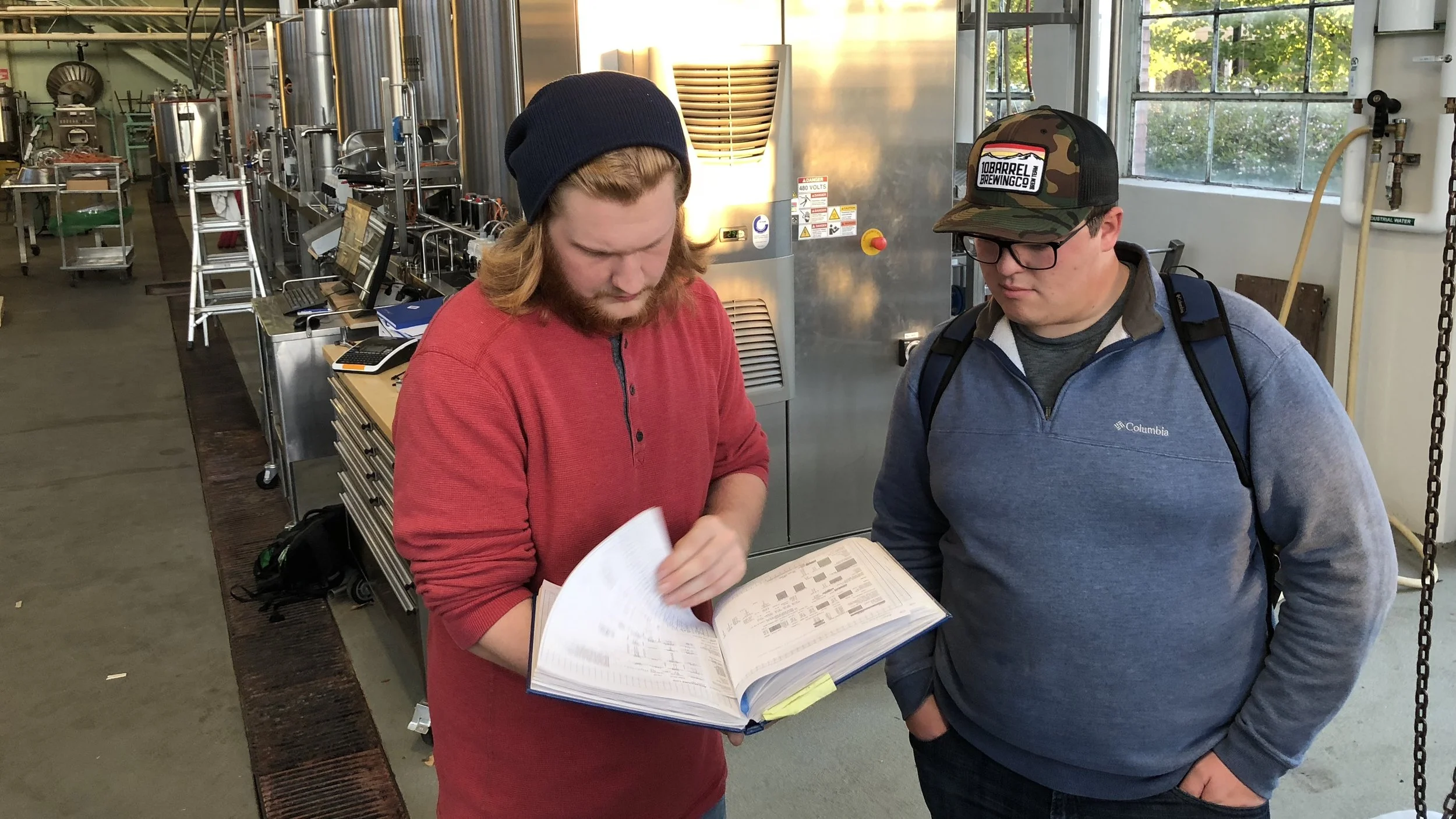 students look through the recipe log book at the fermentation sciences program at Oregon State University (brewery behind them).