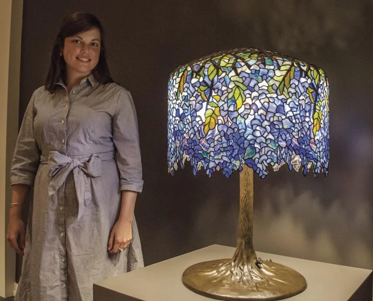 Sally Meyer, adult programs manager at the Museum of the Shenandoah Valley, stands with a Tiffany lamp designed by Clara Driscoll, called Wisteria, which contains 2,000 pieces of glass. Jenny Baker/The Winchester Star