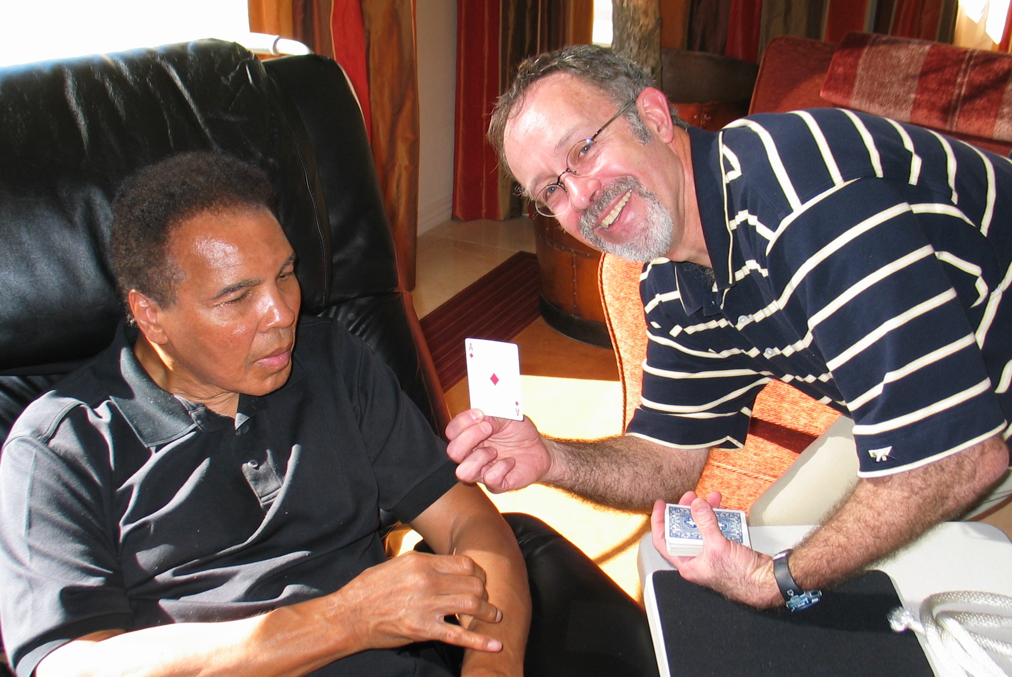 Hondo teaches Muhammad Ali a card trick in his living room in AZ. The Champ loved magic, often pulling coins and silks scarves from behind kids' ears.