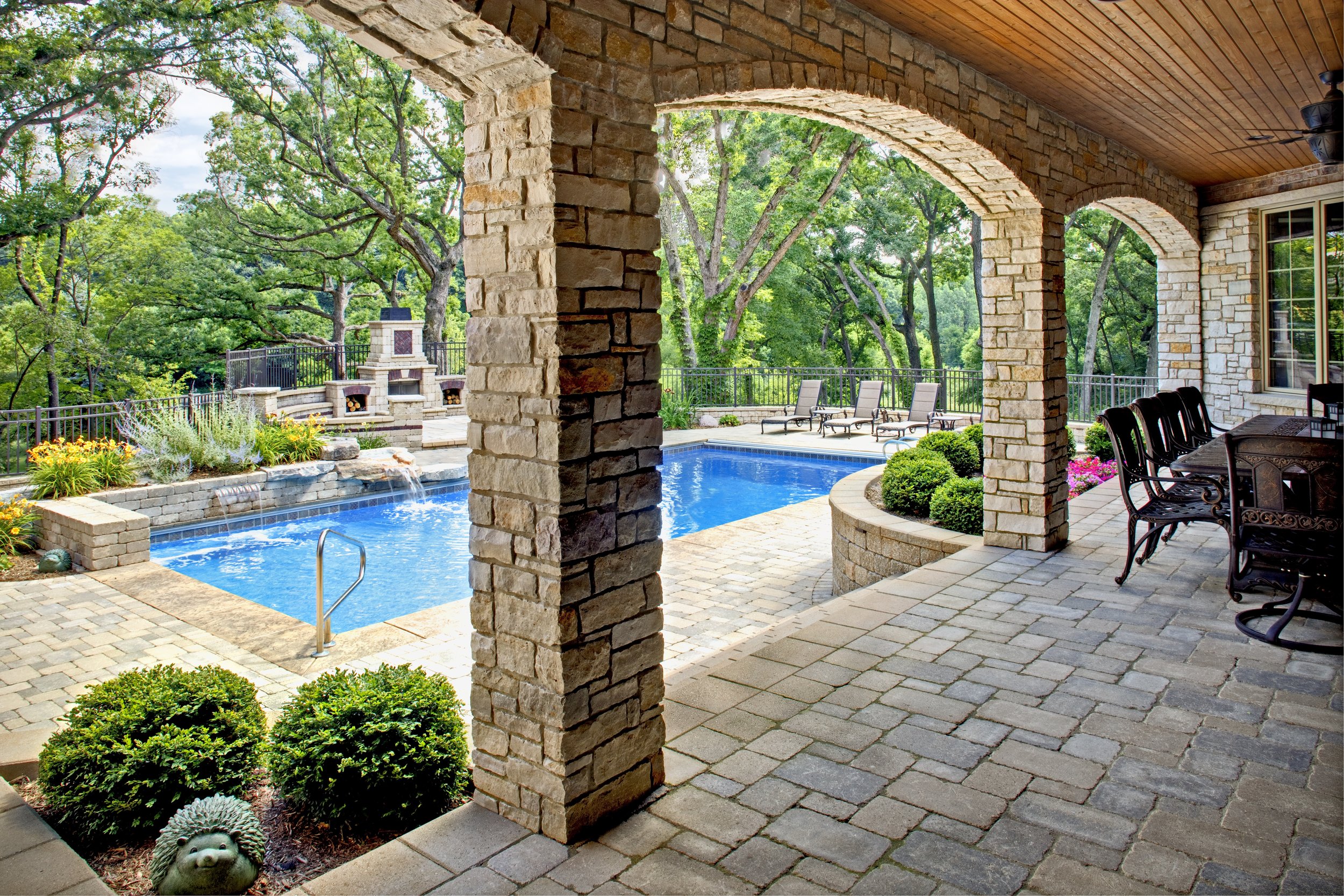 Dream Pool in St. Charles IL.  Custom Stone Arches Lead from Out Door Kitchen.  Unilock Fire Place.  Southampton Builders Geneva IL.