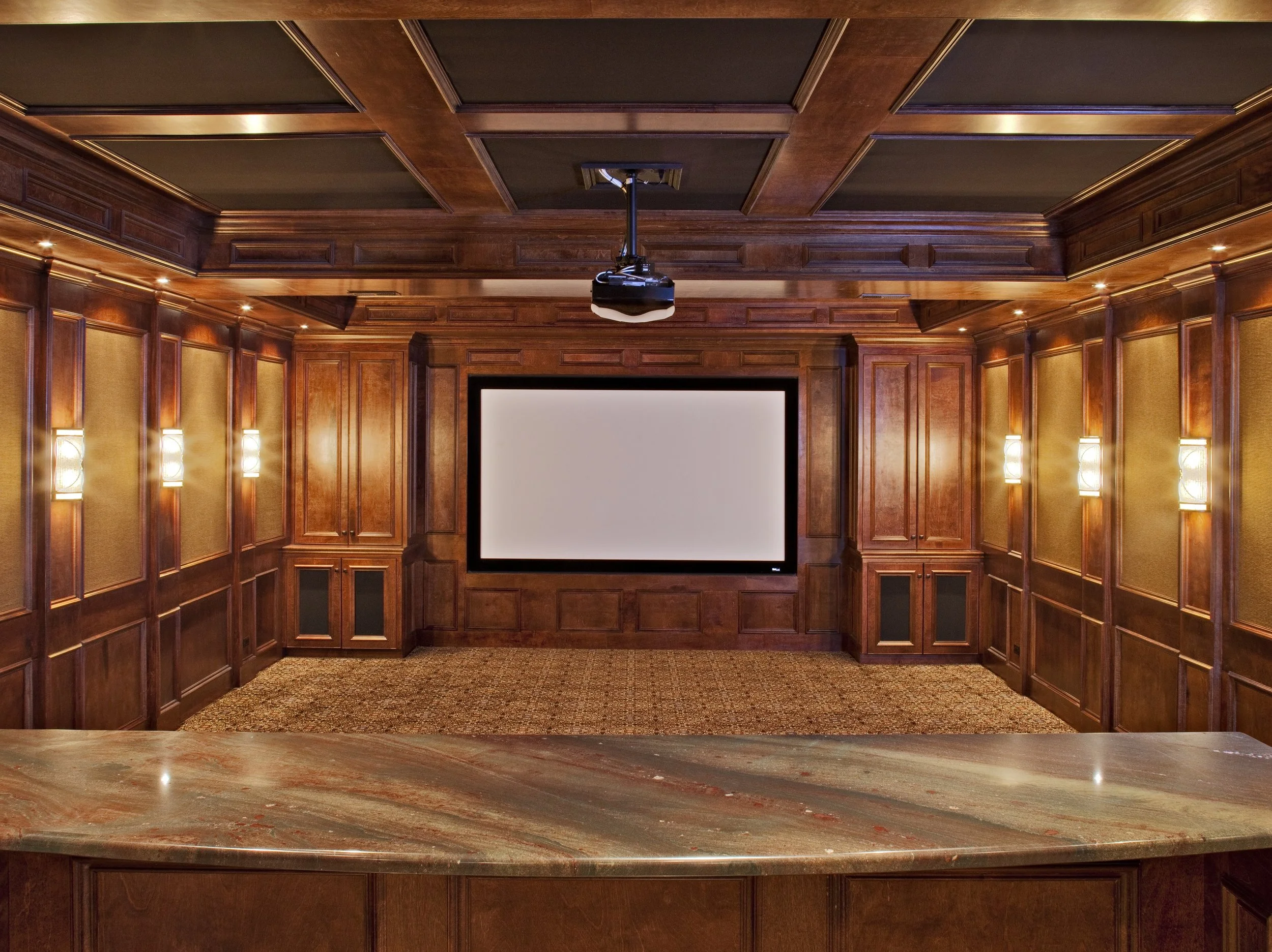 CUSTOM BASEMENT THEATER ROOM WITH WOOD PANELING AND PROJECTOR SCREEN. ELABORATE TRIM WORK AND CUSTOM THEATER SEATS.