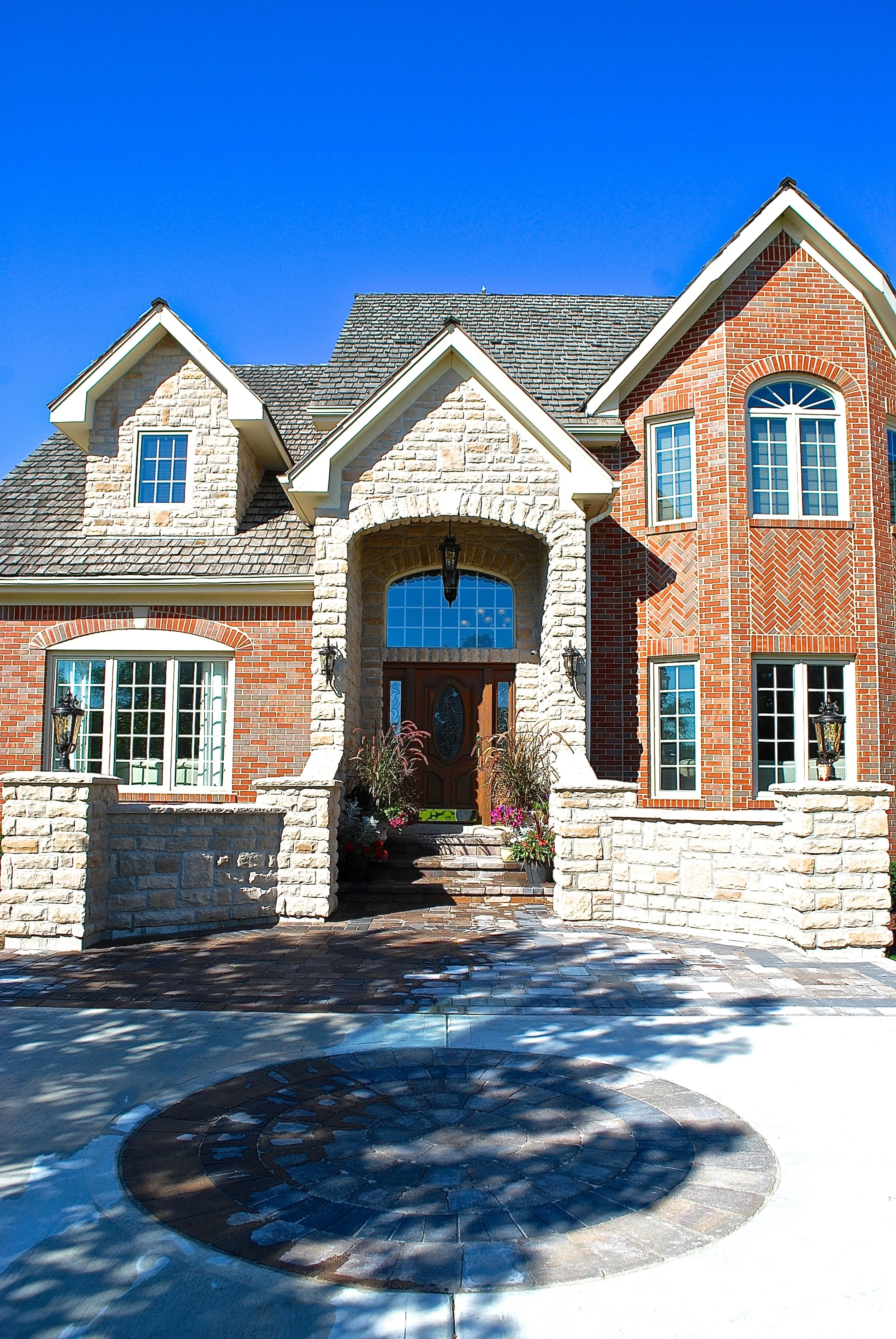 FRONT ENTRY REMODEL WITH NEW CONCRETE DRIVEWAY WITH BRICK PAVER ACCENTS &amp; INLAYS. NEW STONE PILLARS AND STOEN FACADE REMODEL. LIGHTS ON STONE PILLARS
