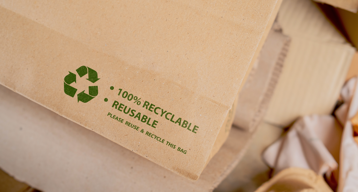 A photo of the edge of a paper mailer showing the green recyclable symbol. The text reads, 100 percent RECYCLABLE REUSABLE, Please reuse and recycle this bag. Print shop West Perth.