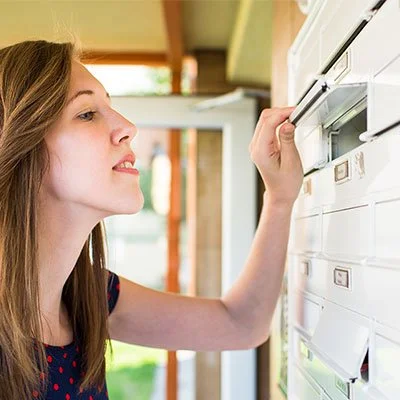 A photo of a young woman who has opened her letterbox and is eagerly peering into it. Print services Perth