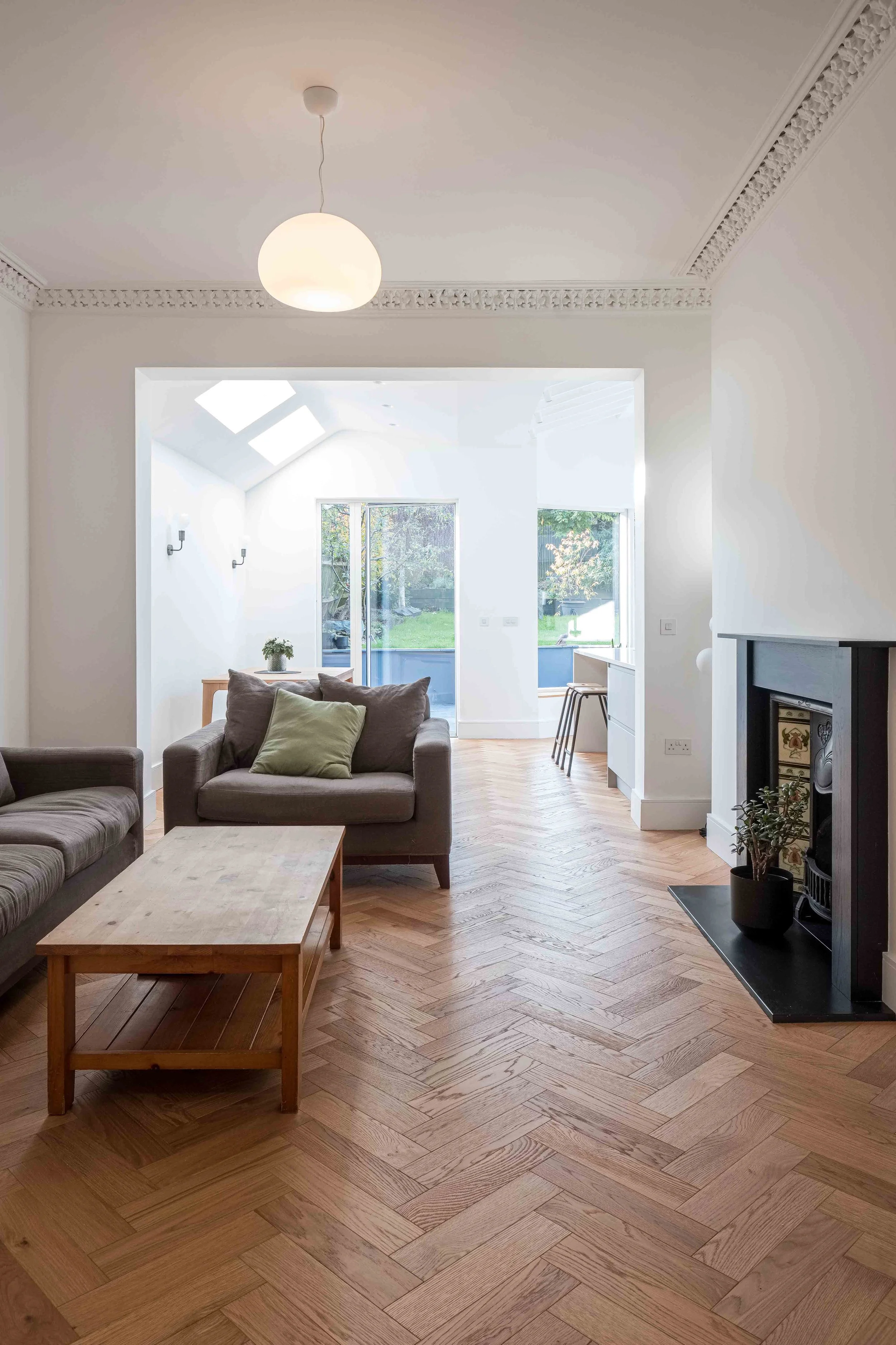 Warm oak herringbone floor and monochrome walls