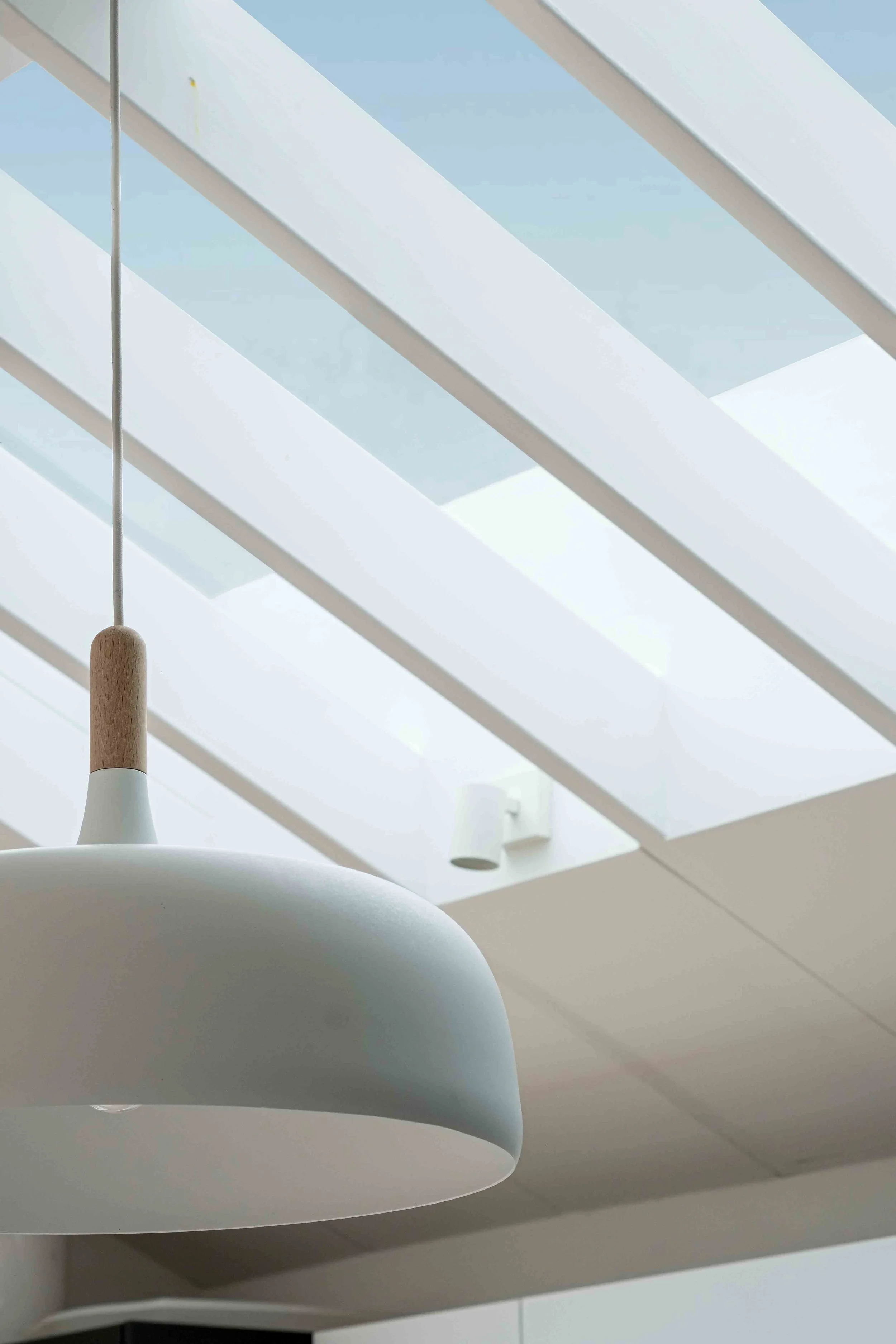 Exposed rafters shading rooflight with white pendant light fitting