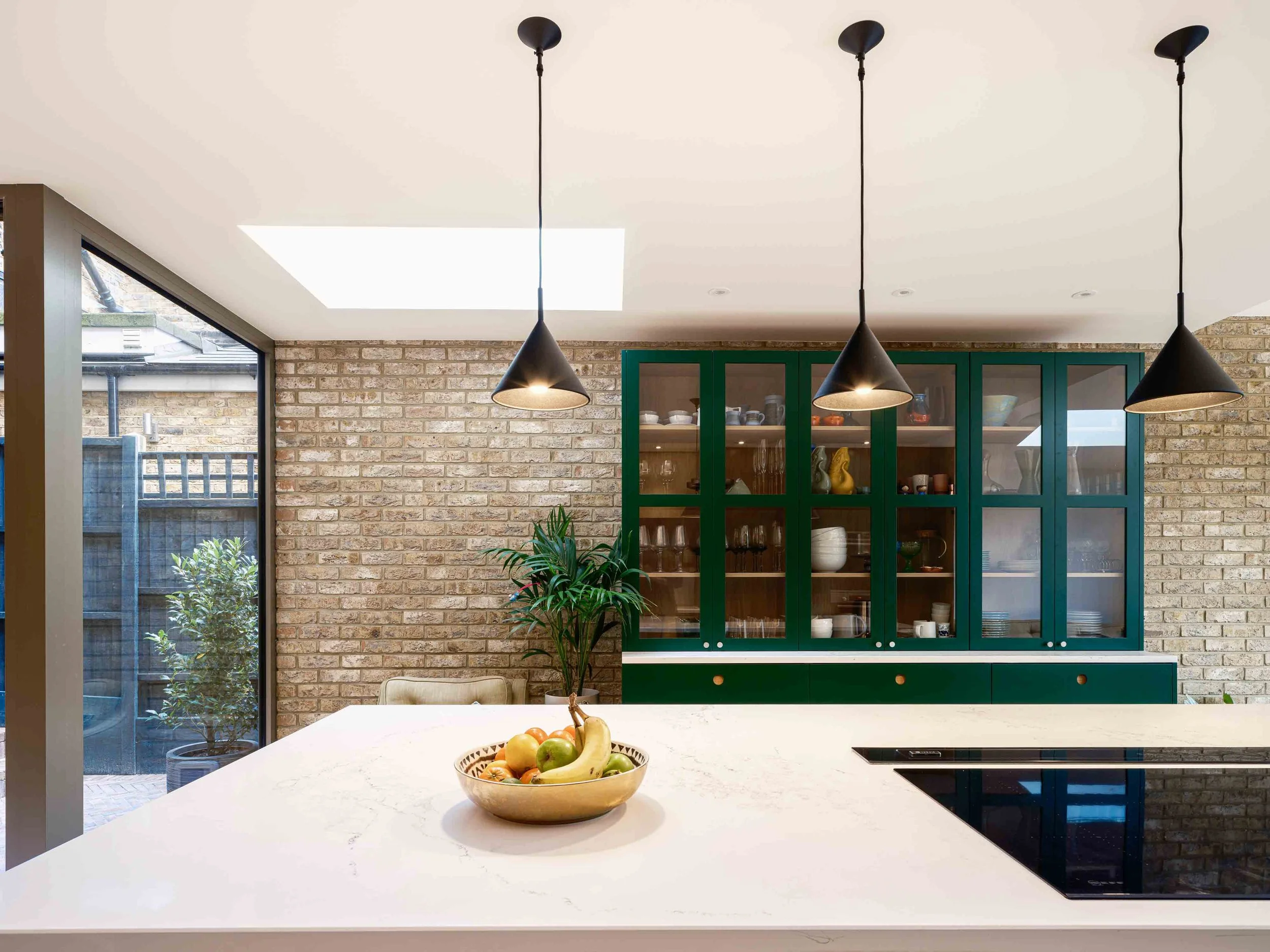 Green glazed kitchen dresser and exposed brickwork