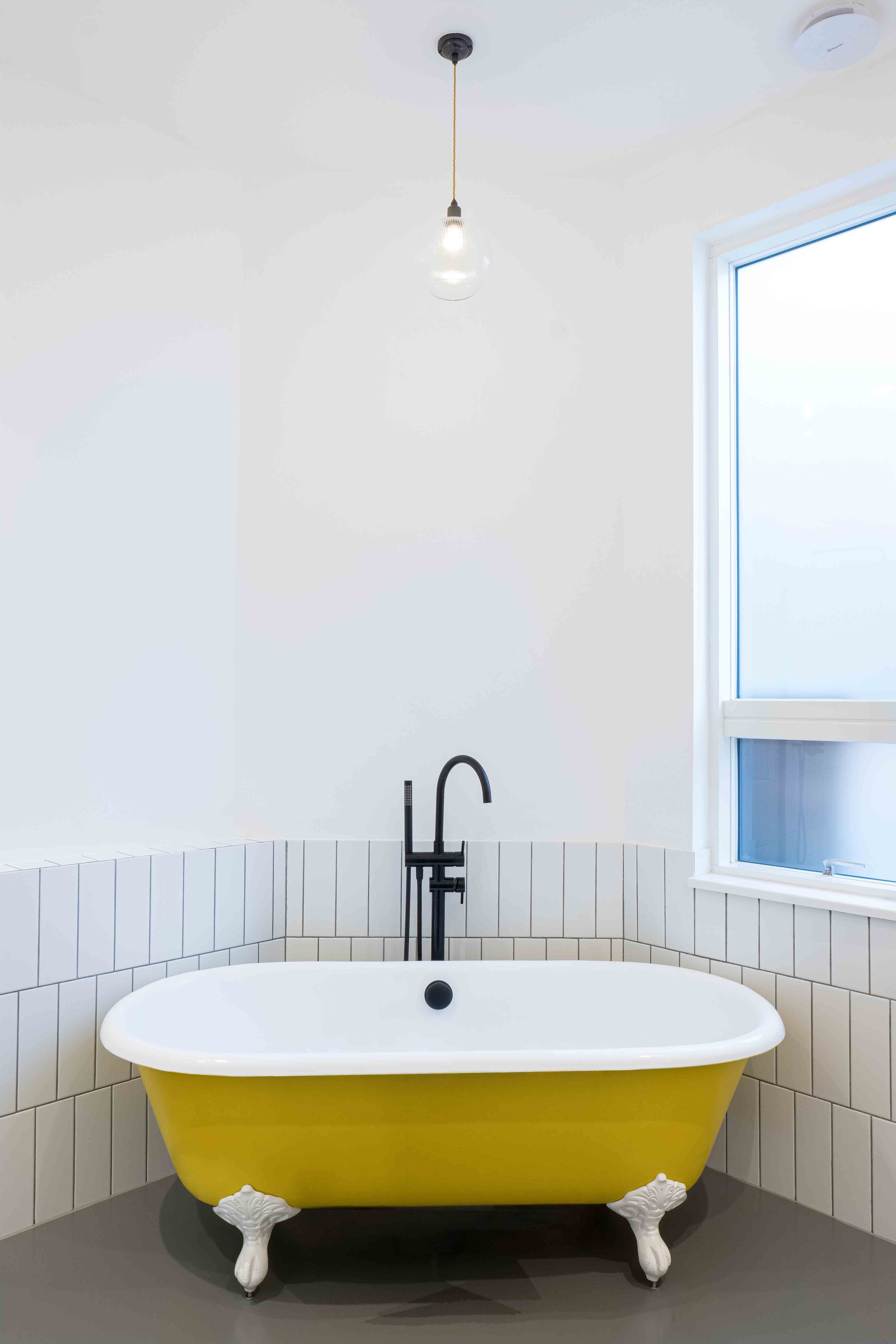 Monochromatic bathroom with mustard yellow bath