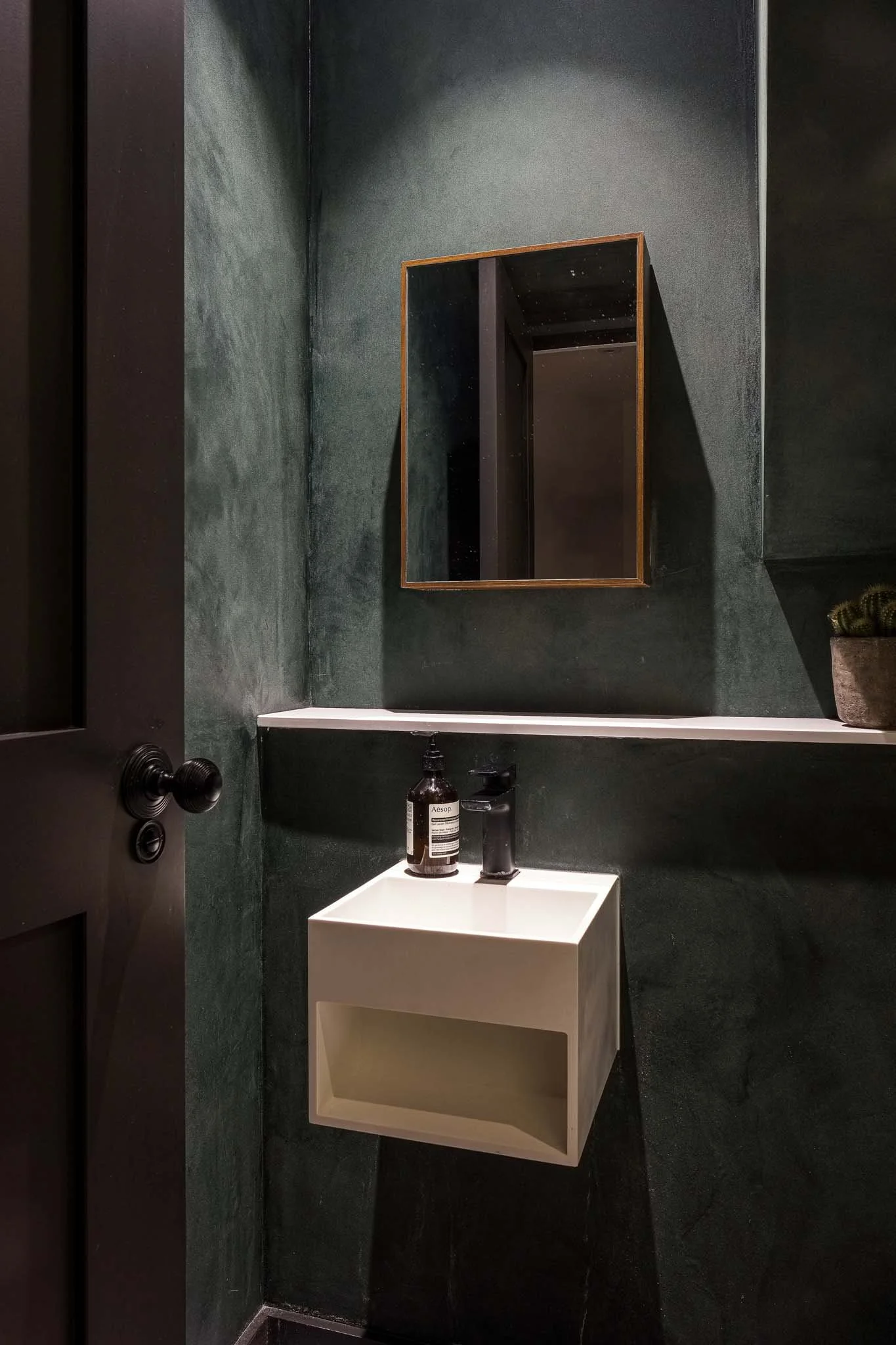 Nordic plaster finish in deep green with stone basin