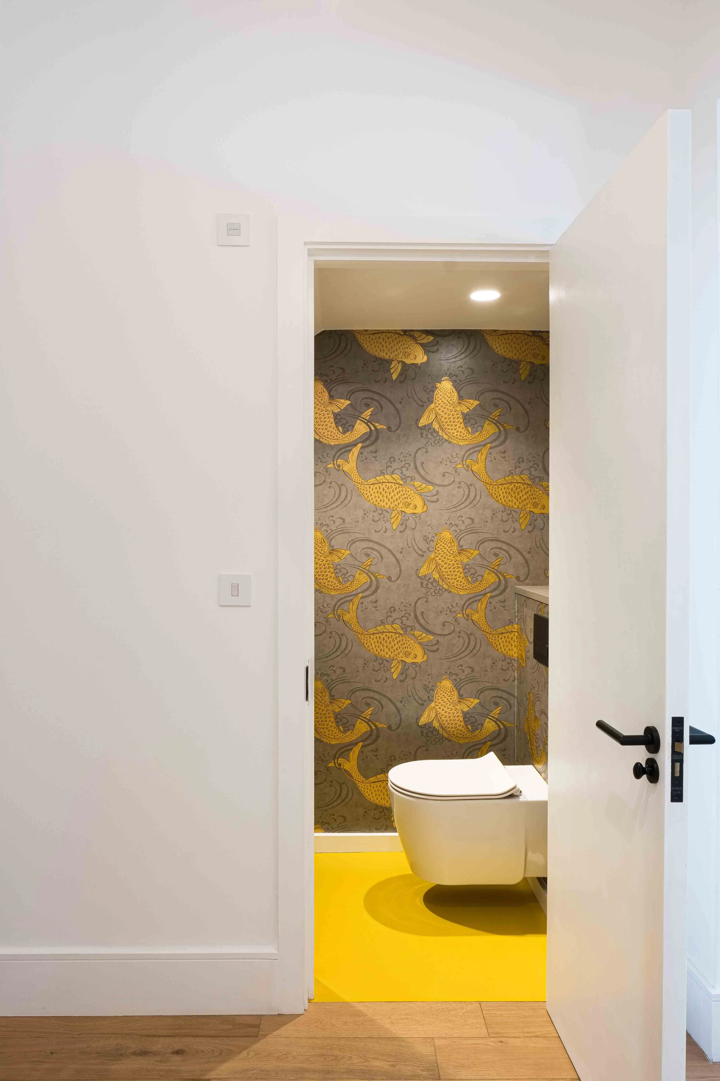 Yellow rubber flooring and bold fish wallpaper in wc