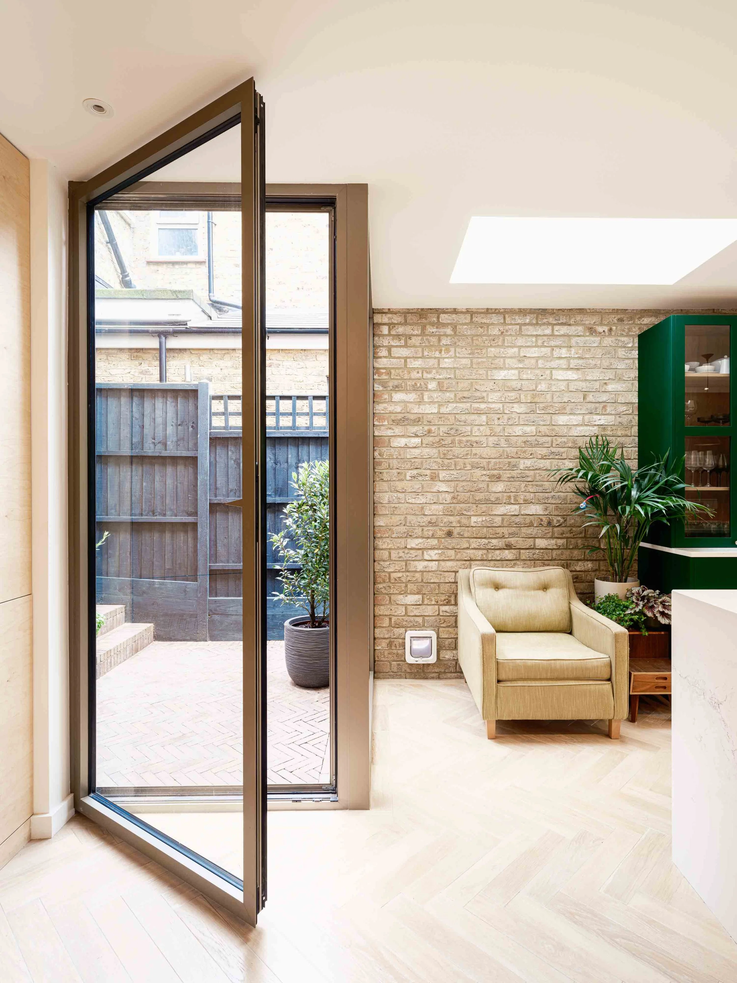 Corner glazed door with pale oak floor and exposed brick