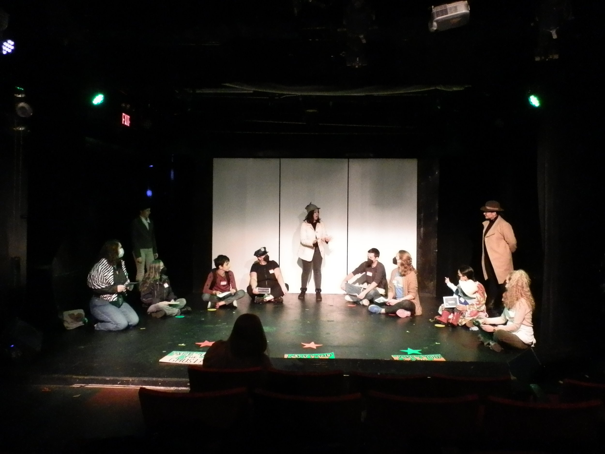  Lluvia Almanza as Detective Sharpe with an audience of suspects in  The Mystery of the Green Teeth Ghost.  Photo by Robert René Galván. 