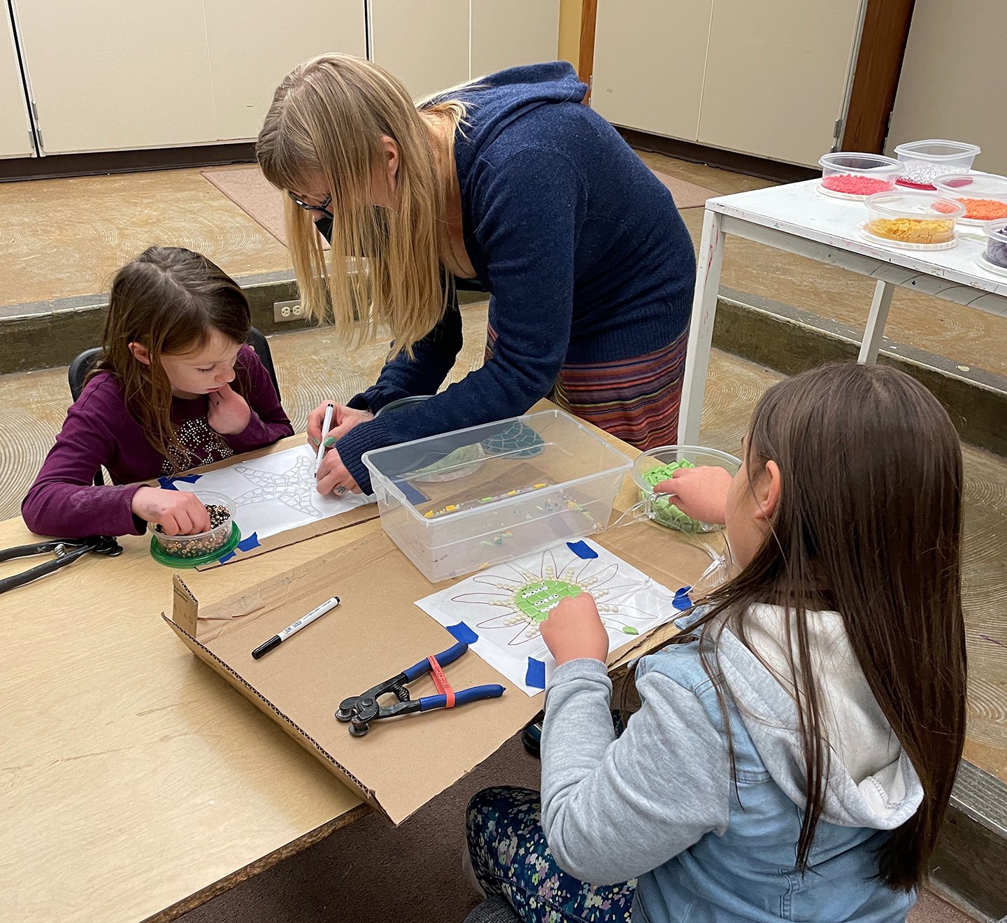    Jenn helps one of the girls mark a tile for cutting.   