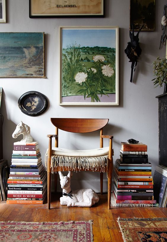 Stacks of books on the floor next to a chair