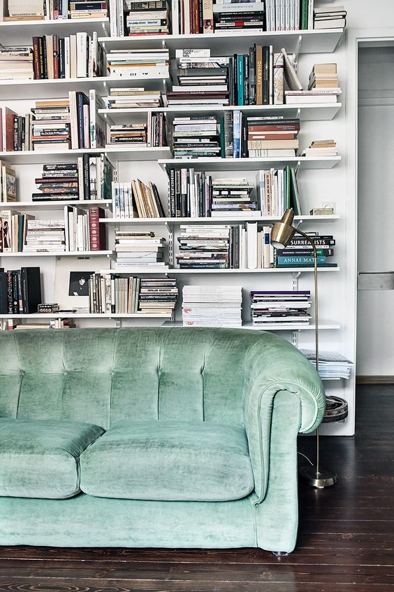 Full bookshelf behind green sofa
