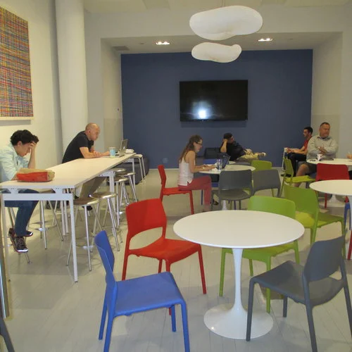 Engaging spaces, such as a colorful cafe at Civic Hall, encourage collaboration and cross-pollination across disciplines while providing an alternative workspace for untethered knowledge workers.