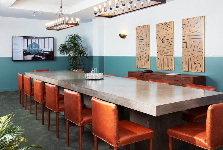 Long gray table with several orange chairs