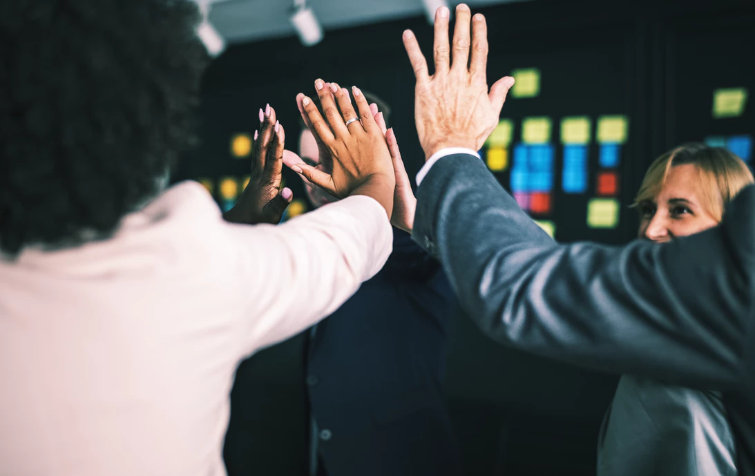 business teammates celebrating with high fives in an office area
