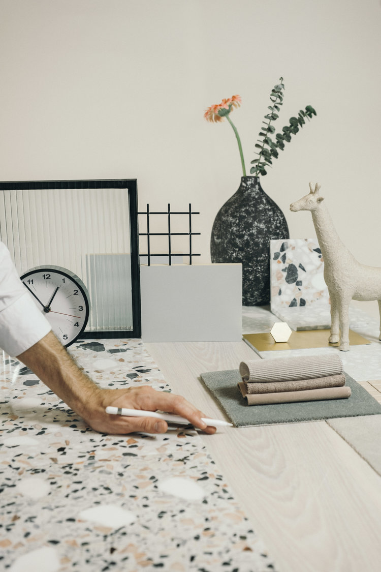 designer standing at workspace with textile and stone samples