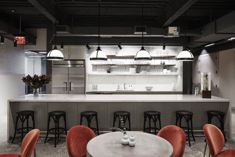black and white kitchen area with bistro tables and orange chairs