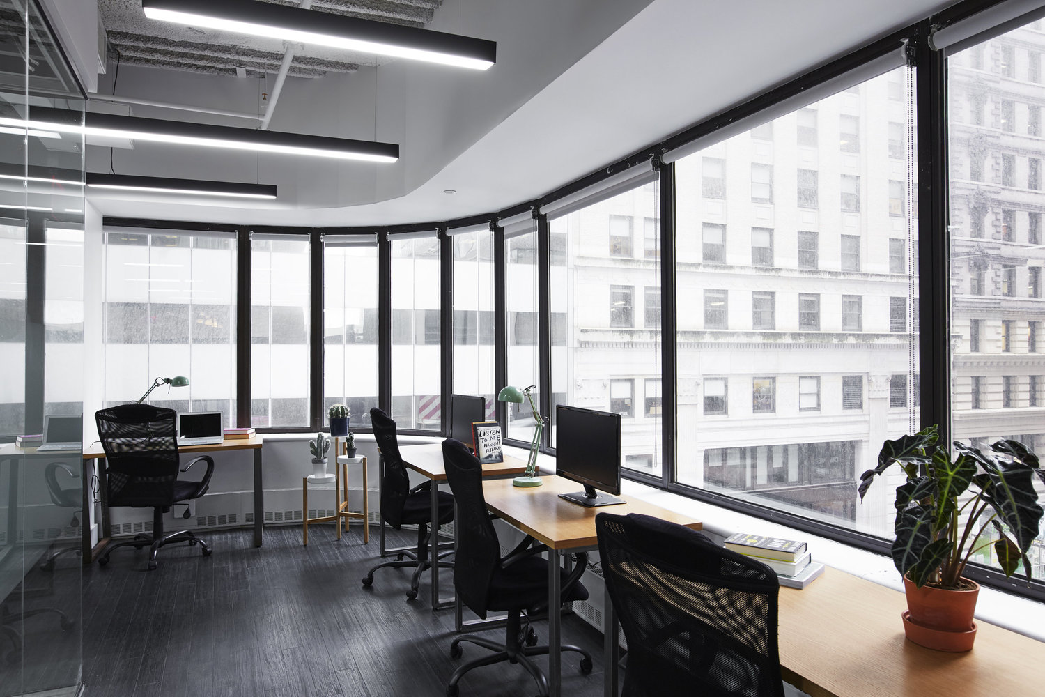 large black and white shared office space with wrap-around windows, desks and chairs