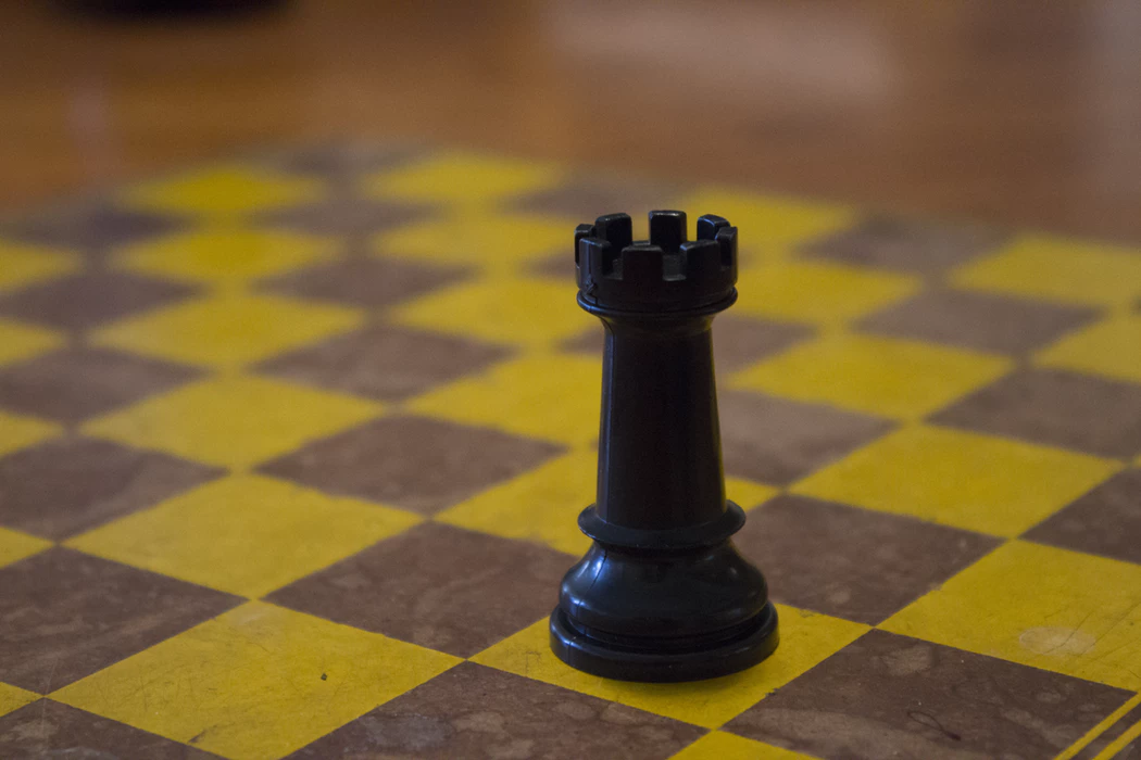 black chess game piece on yellow chess board