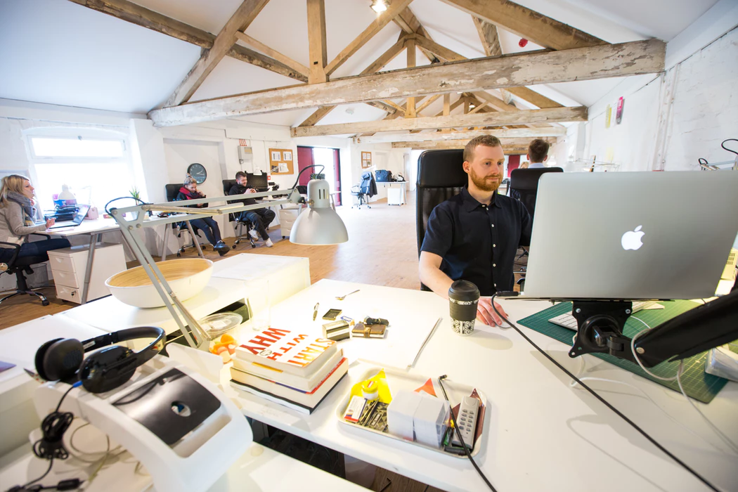 team members working on projects in different areas of an open office plan work area